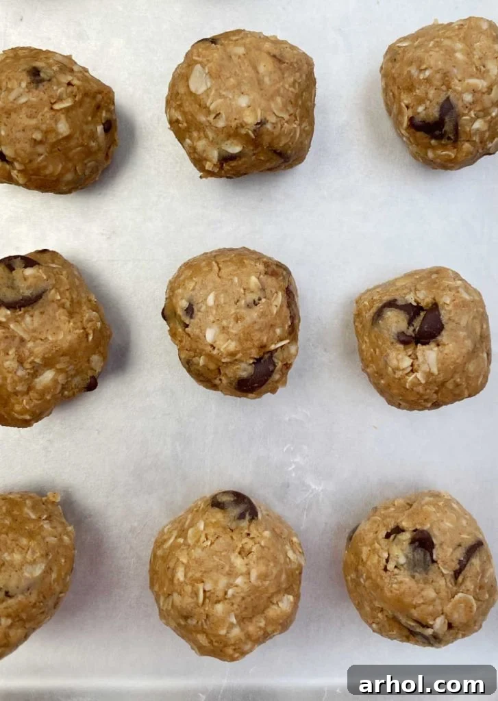 Freshly rolled peanut butter chocolate chip energy balls neatly arranged on a baking sheet lined with wax paper.