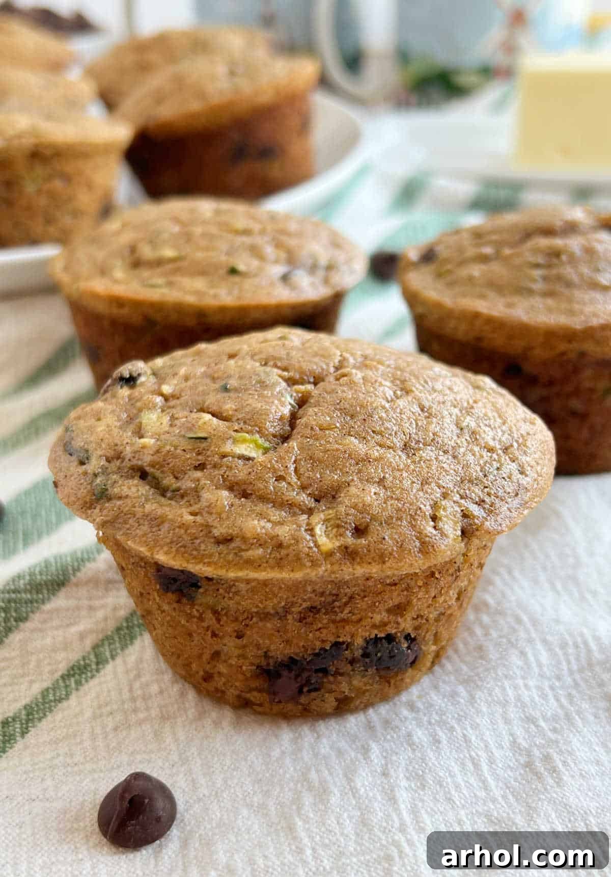 Beautifully baked zucchini banana muffins with melted chocolate chips, resting on a rustic wooden table.