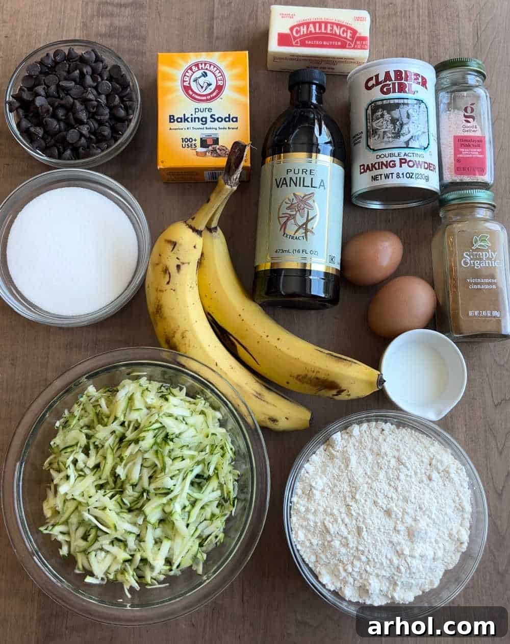 Freshly grated zucchini, ripe bananas, and other essential baking ingredients laid out on a kitchen counter, ready for muffin preparation.