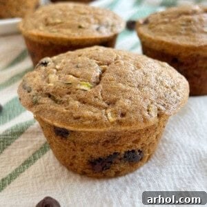 Close-up of a zucchini banana chocolate chip muffin with a golden top and visible chocolate.