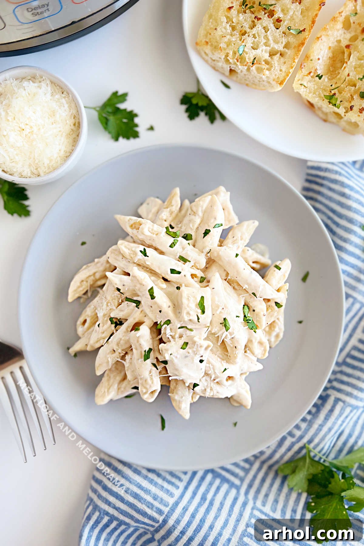 Instant Pot Chicken Alfredo pasta served with garlic bread and Parmesan on the table