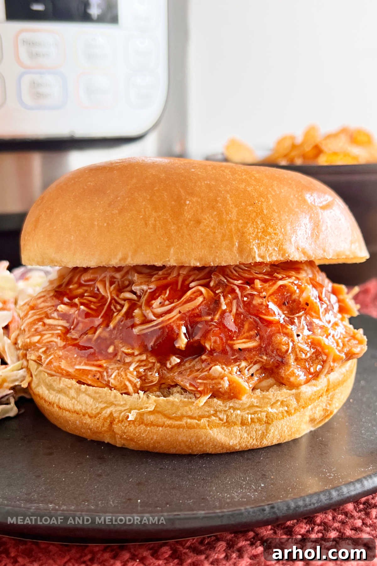 Instant Pot pulled BBQ chicken sandwich on a toasted brioche bun, served on a rustic table