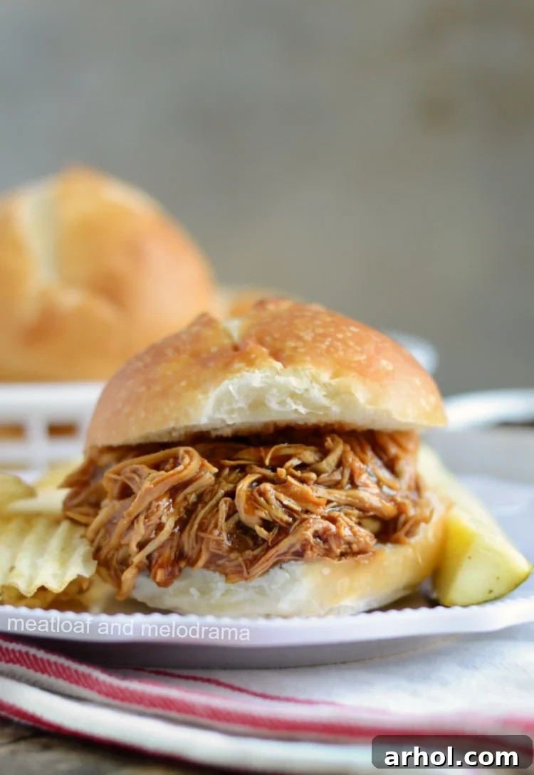 A small pulled Instant Pot BBQ chicken slider on a plate, garnished with fresh herbs, ideal for appetizers