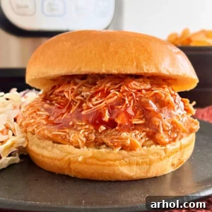 Instant Pot pulled BBQ chicken sandwich on brioche bun with coleslaw on a black plate