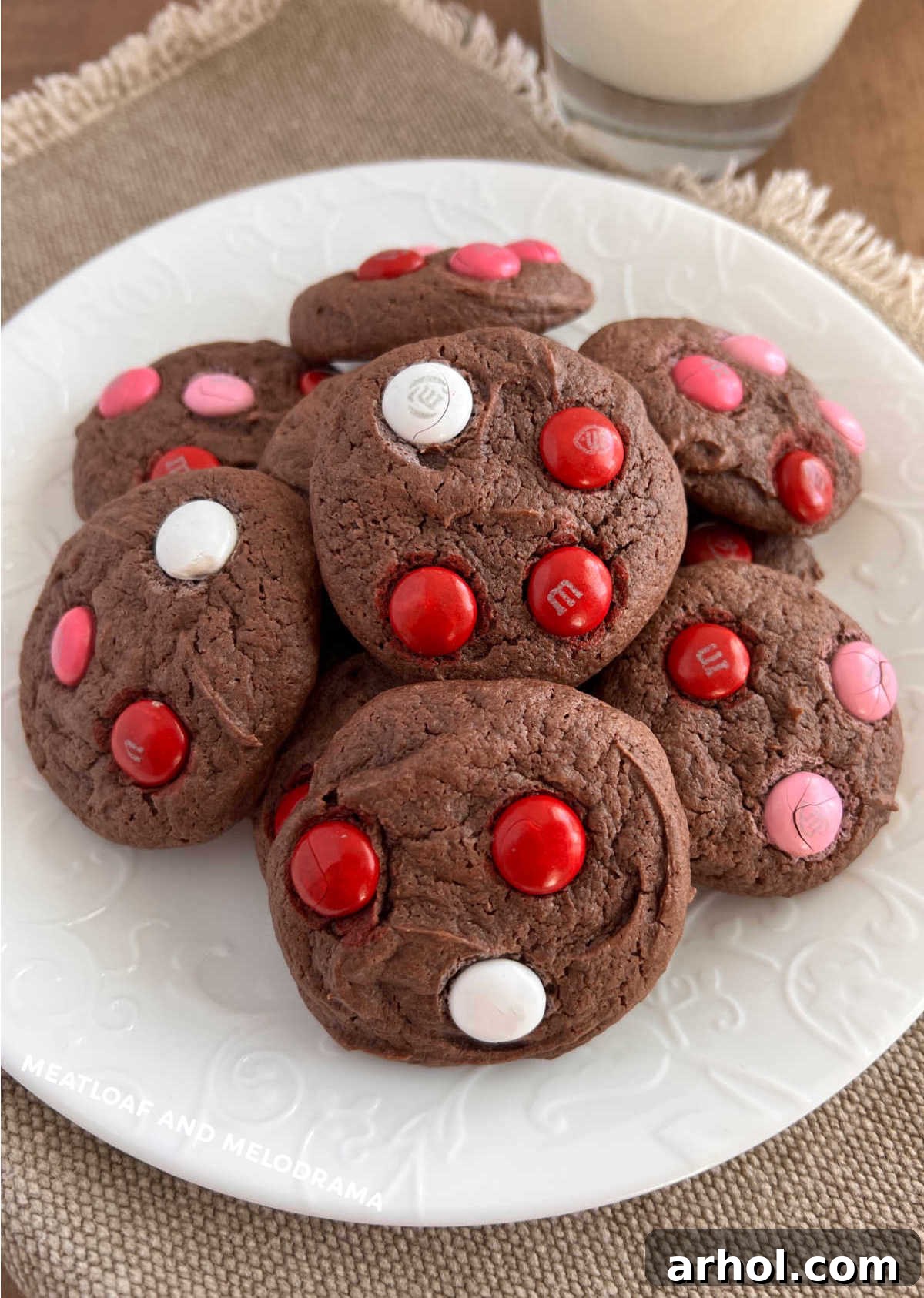 Delicious chocolate cake mix cookies adorned with vibrant red, white, and pink M&M candies, arranged invitingly on a white surface.