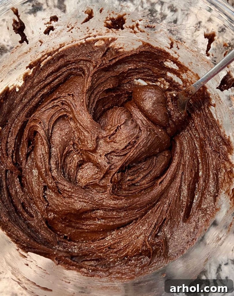 Mixing chocolate cookie dough in a large bowl, showing the thick, rich consistency.