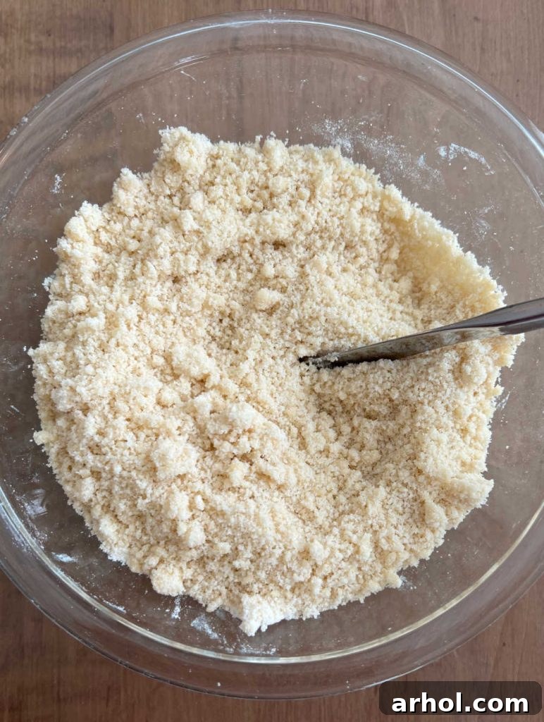 Summertime Peach Crisp Delight 4 Cutting cold butter into a flour mixture with a knife in a medium mixing bowl to create a crumbly peach crisp topping.