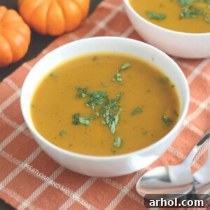 Bowl of Instant Pot pumpkin soup on the table, garnished with herbs.