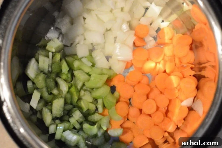 Chopped celery, carrots, and onions (mirepoix) sautéing in the Instant Pot, forming the base for homemade turkey soup.