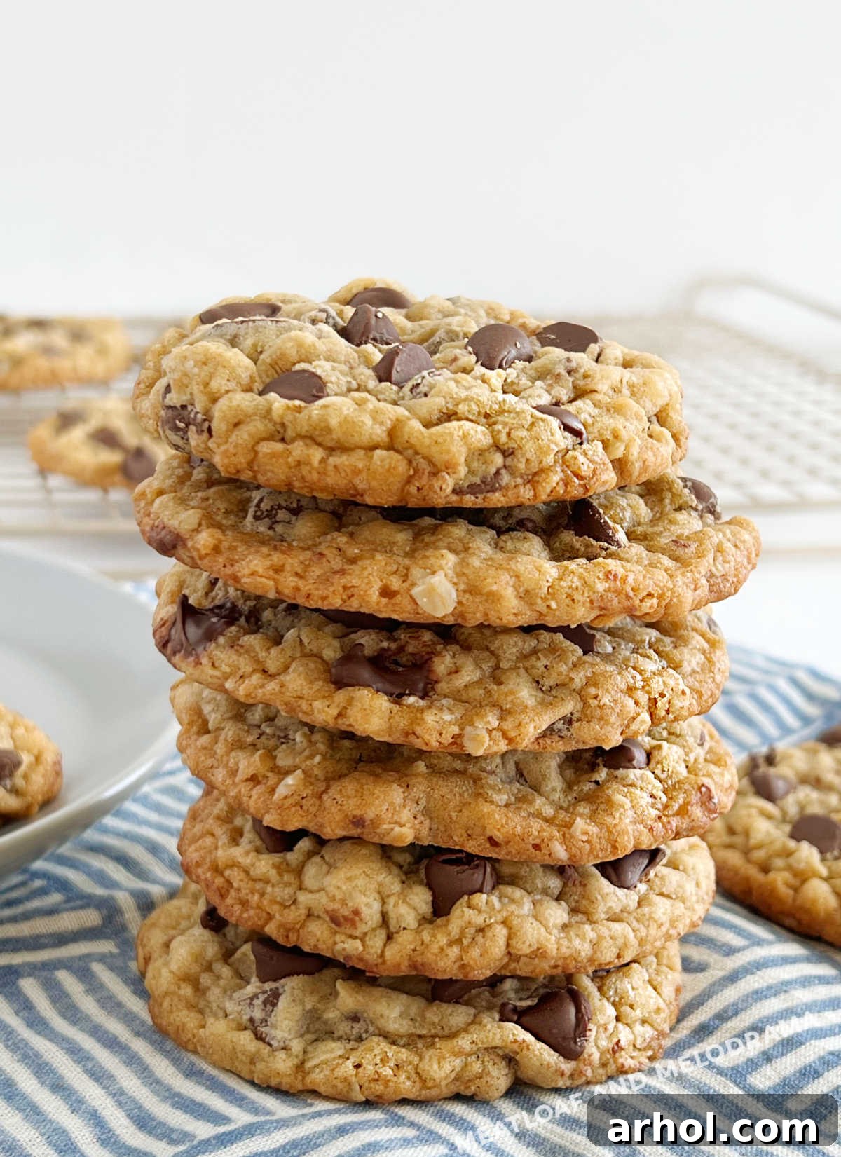 Stack of warm, chewy oatmeal chocolate chip cookies on a rustic table, ready to be enjoyed.