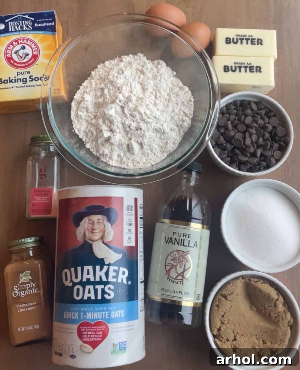 Arrangement of key ingredients for oatmeal chocolate chip cookies: Quaker oats, all-purpose flour, baking soda, softened butter, vanilla extract, brown sugar, granulated sugar, chocolate chips, cinnamon, and sea salt.