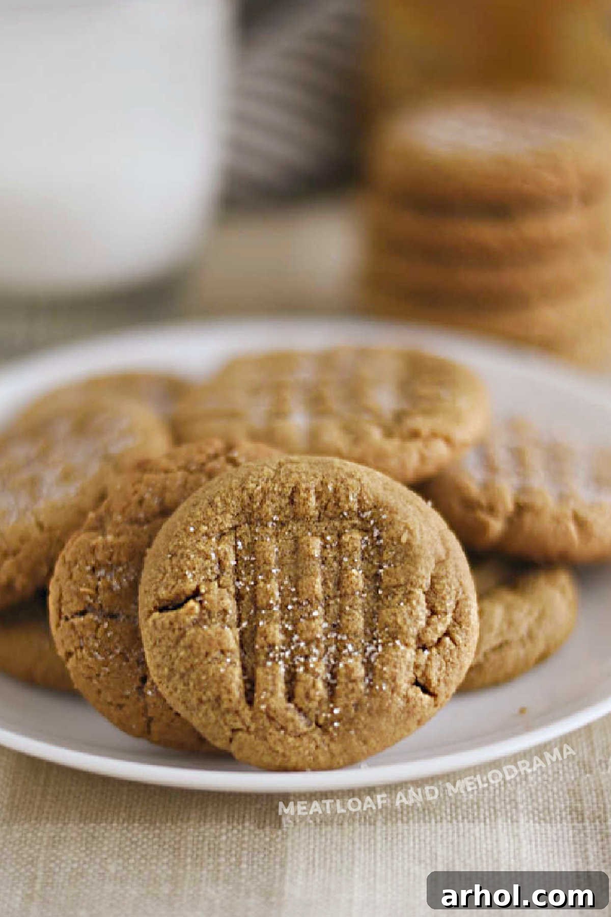 The Easiest 4 Ingredient Peanut Butter Cookies 2 Delicious flourless peanut butter cookies arranged neatly on a plate on a rustic wooden table, ready to be enjoyed.