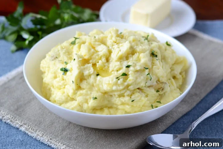 Instant Pot mashed potatoes with butter in a white bowl, garnished with fresh herbs