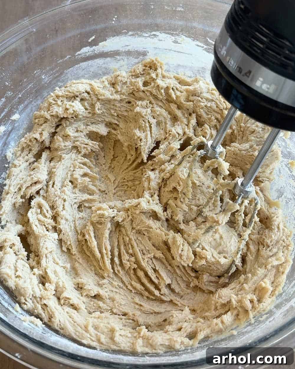 Mixing cookie dough ingredients with an electric mixer in a large bowl.
