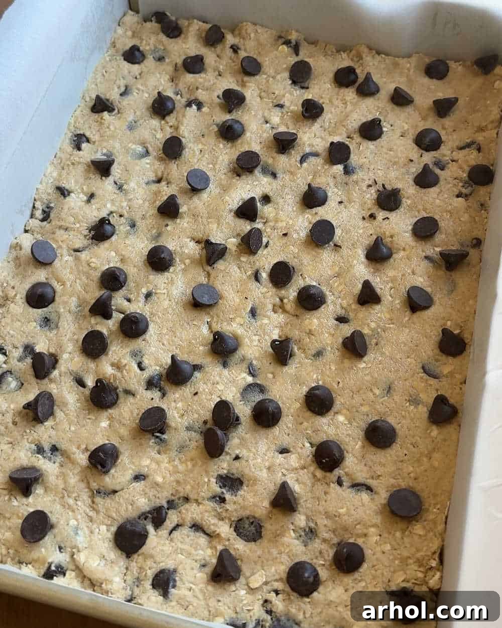 Cookie dough pressed evenly into a parchment-lined baking pan.