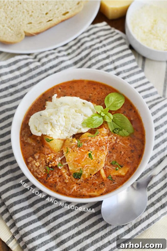 Easy Instant Pot Lasagna Soup 3 A bowl of lasagna soup with a dollop of ricotta cheese mixture on top and a sprig of basil