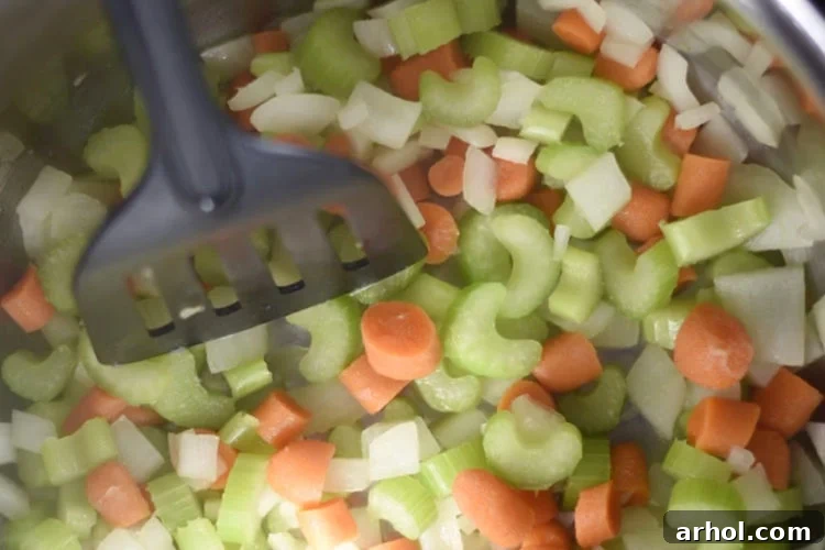Chopped onions, carrots, and celery being sautéed in an Instant Pot to build a flavorful base for ham and lentil soup.