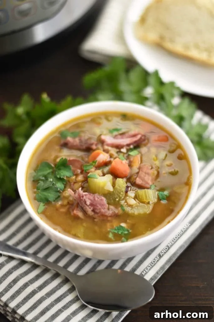 Instant Pot Ham and Lentil Soup with visible carrots and celery, ready to be served in a white bowl.