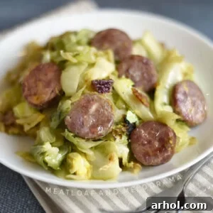 Pan-fried kielbasa and cabbage on a white plate, served as a meal.