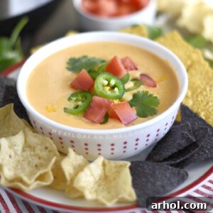Instant Pot Queso Dip in a bowl with tortilla chips and tomatoes and jalapeno peppers