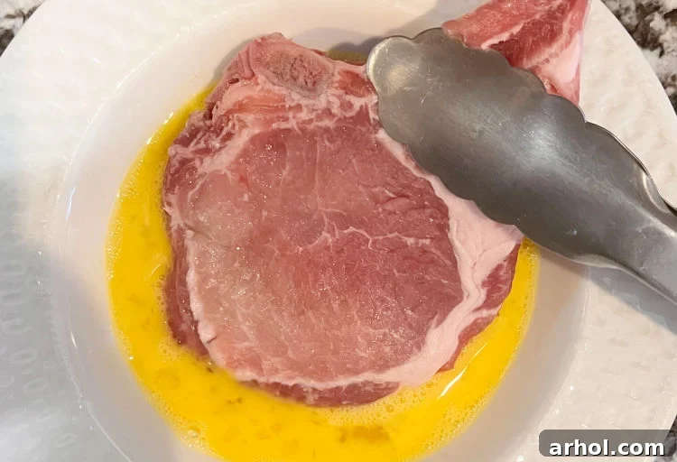 dip pork chop into eggs in shallow bowl with tongs