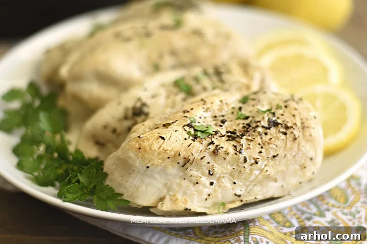 Perfectly cooked Instant Pot chicken breasts on a white platter with fresh lemon slices.
