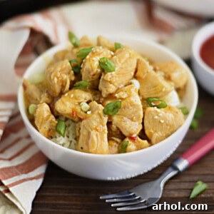 Instant Pot orange chicken in a white bowl over rice with scallions