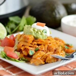 instant pot chicken enchilada pasta on white plate with guacamole, sour cream, tomatoes