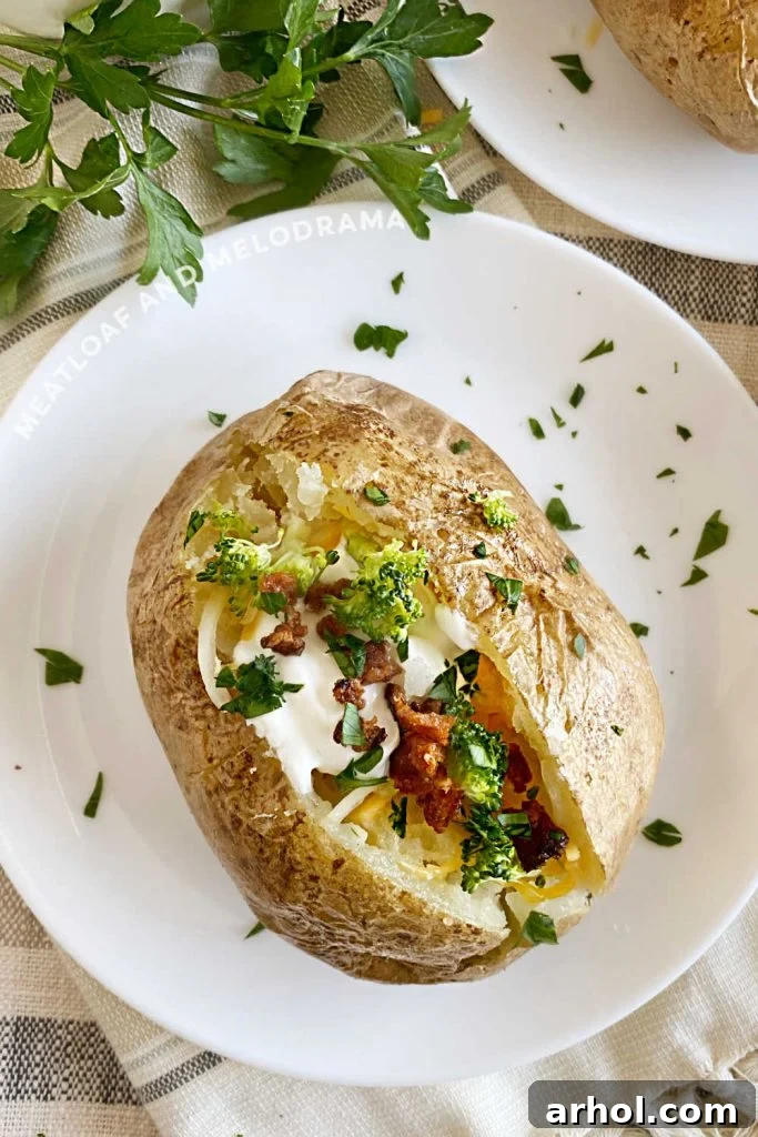Baked potato with sour cream, bacon, broccoli, and cheese on a white plate with parsley garnish, highlighting a perfect fluffy texture.
