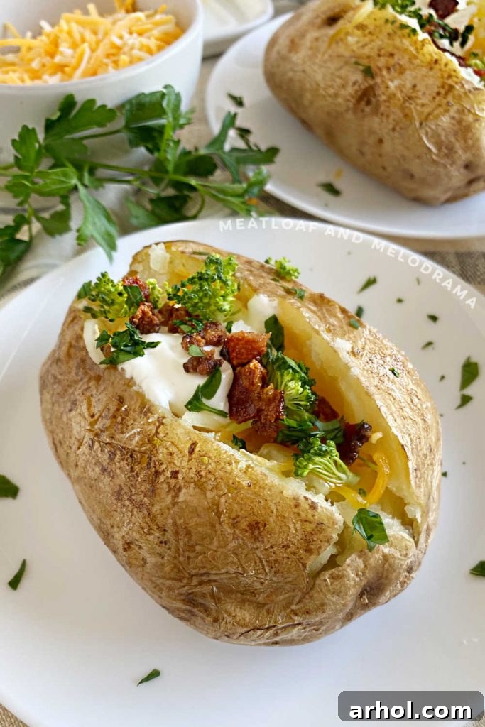 A beautifully loaded baked potato overflowing with cheese, sour cream, and crispy bacon bits on a white plate, ready to be enjoyed.