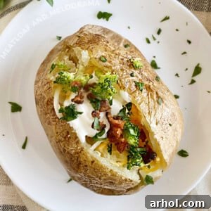 A microwave baked potato loaded with broccoli, sour cream, shredded cheese, and crispy bacon bits, served on a white plate.