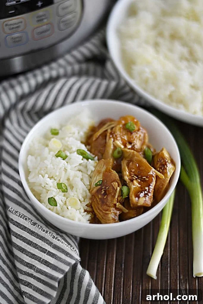 A vibrant bowl of Instant Pot Teriyaki Chicken served over fluffy jasmine rice, garnished with fresh green scallions and sesame seeds.