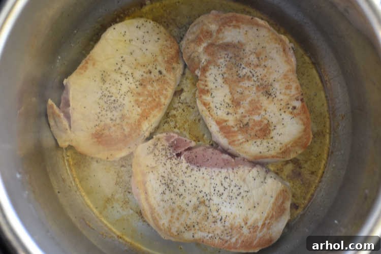 Searing boneless pork chops in the Instant Pot liner, achieving a golden brown crust for maximum flavor before pressure cooking.