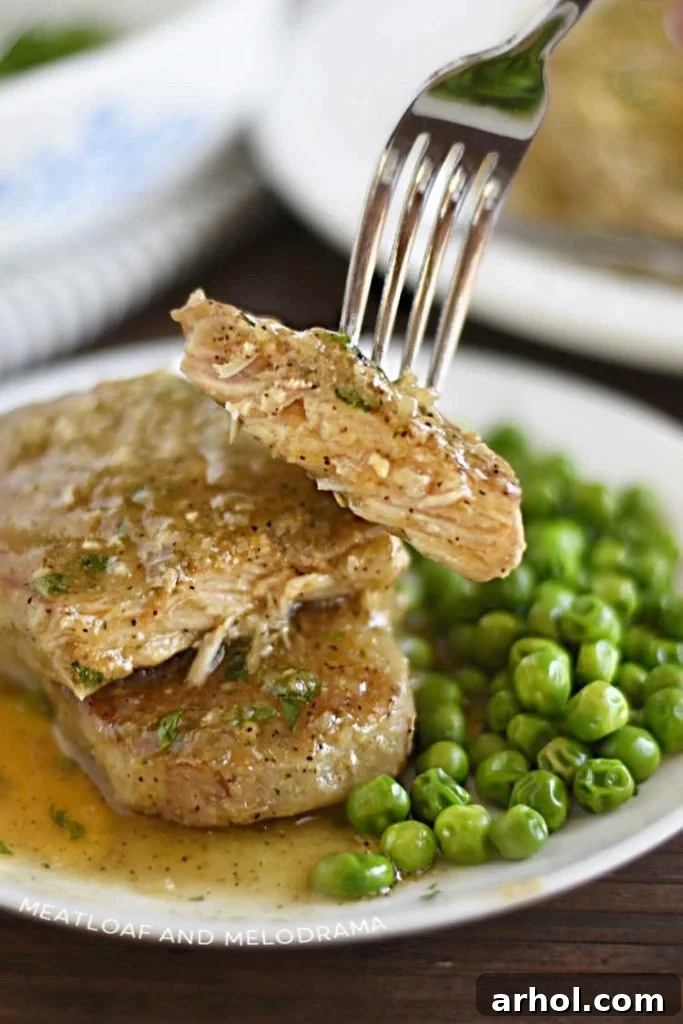 A fork holding a slice of tender boneless Instant Pot pork chop covered in gravy, highlighting the meal's deliciousness.