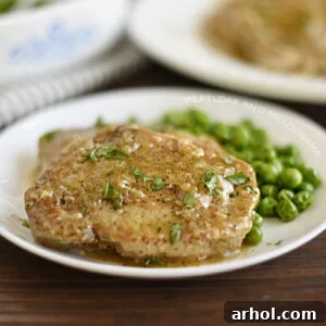 Instant Pot boneless pork chops on a plate with gravy and peas