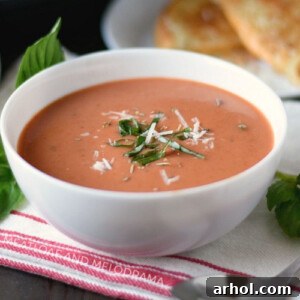 Instant Pot Creamy Tomato Basil Soup in a white bowl, garnished with Parmesan and fresh basil.