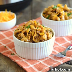 Instant Pot BBQ Macaroni and Beef in white bowls, topped with melted cheddar cheese.