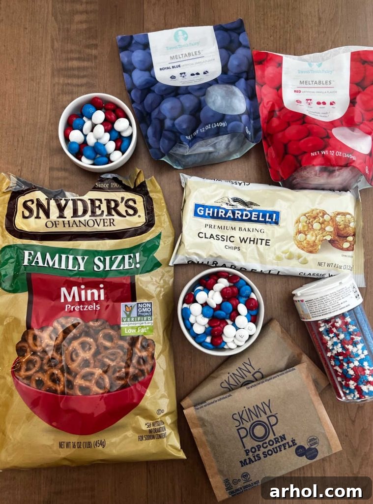 Stars and Stripes Popcorn Treat 3 Close-up of popcorn, pretzels, white chocolate chips, red and blue candy melts, and star sprinkles laid out as ingredients for Patriotic Popcorn