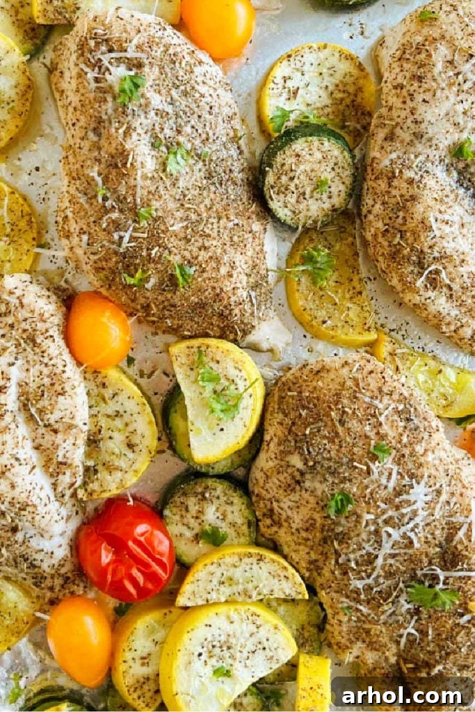 A vibrant sheet pan filled with golden-brown baked chicken, tender zucchini slices, bright yellow squash, and burst grape tomatoes, ready to serve.