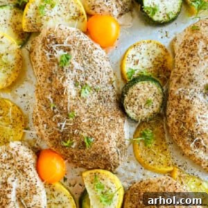 Baked chicken and zucchini with yellow squash and grape tomatoes on a sheet pan.