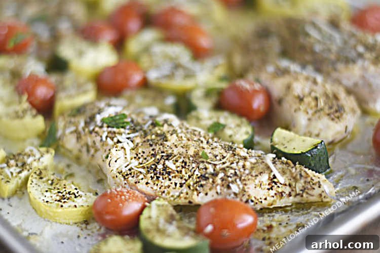 A serving of baked chicken with zucchini, yellow squash, and grape tomatoes, plated beautifully and ready to enjoy.