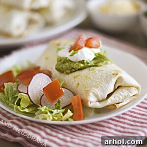 Crispy Air Fryer Chicken Chimichanga topped with sour cream and guacamole, served on a white plate.