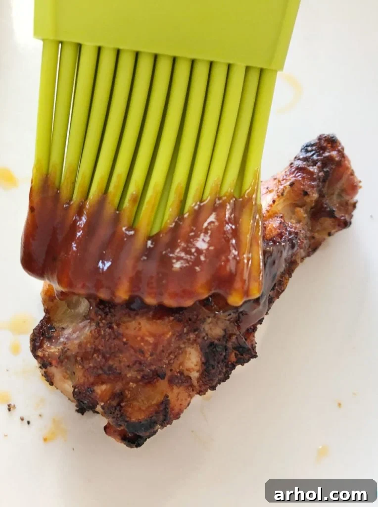 Expertly brushing a freshly air fried chicken wing with glossy BBQ sauce