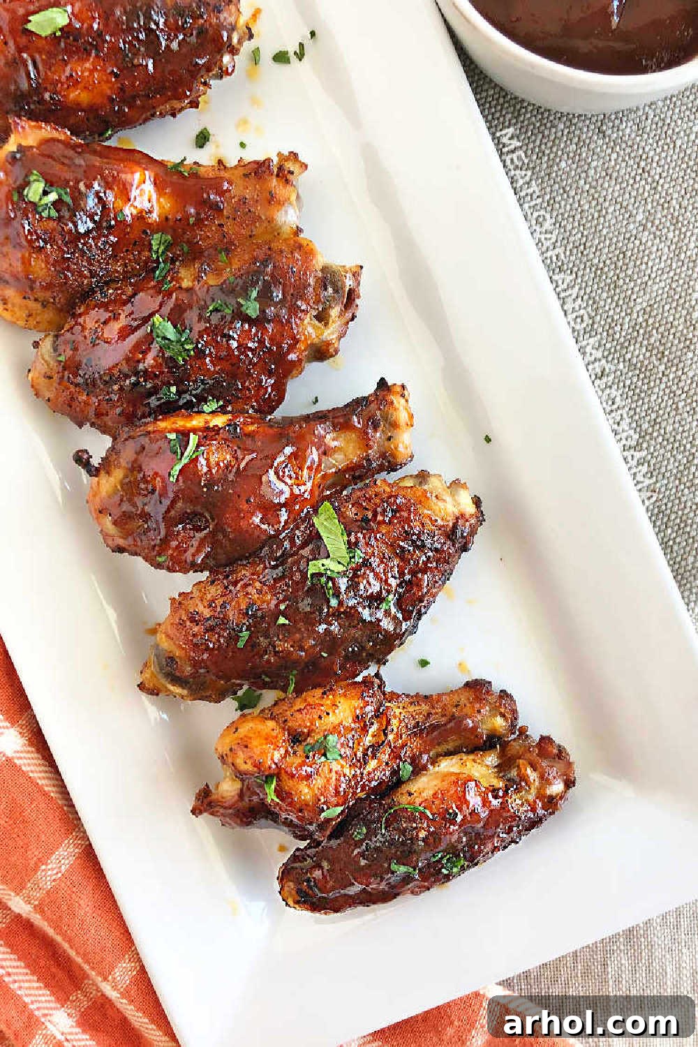 A vibrant platter of air fryer chicken wings generously coated in BBQ sauce, ready for serving