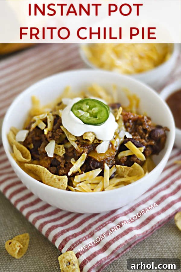 A delicious Instant Pot Frito Chili Pie in a bowl, featuring crisp corn chips, a rich layer of chili, melted cheese, and a swirl of sour cream.