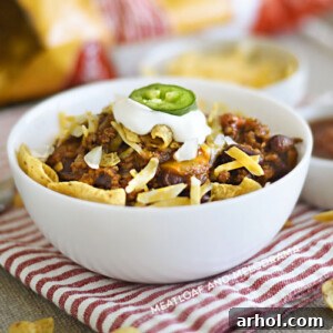 A bowl of Instant Pot Frito Chili Pie with corn chips, cheese, and sour cream