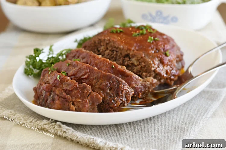 Close-up of a tender slice of favorite meatloaf topped with a rich, savory tomato sauce glaze, presented on a white platter, highlighting its juicy texture.