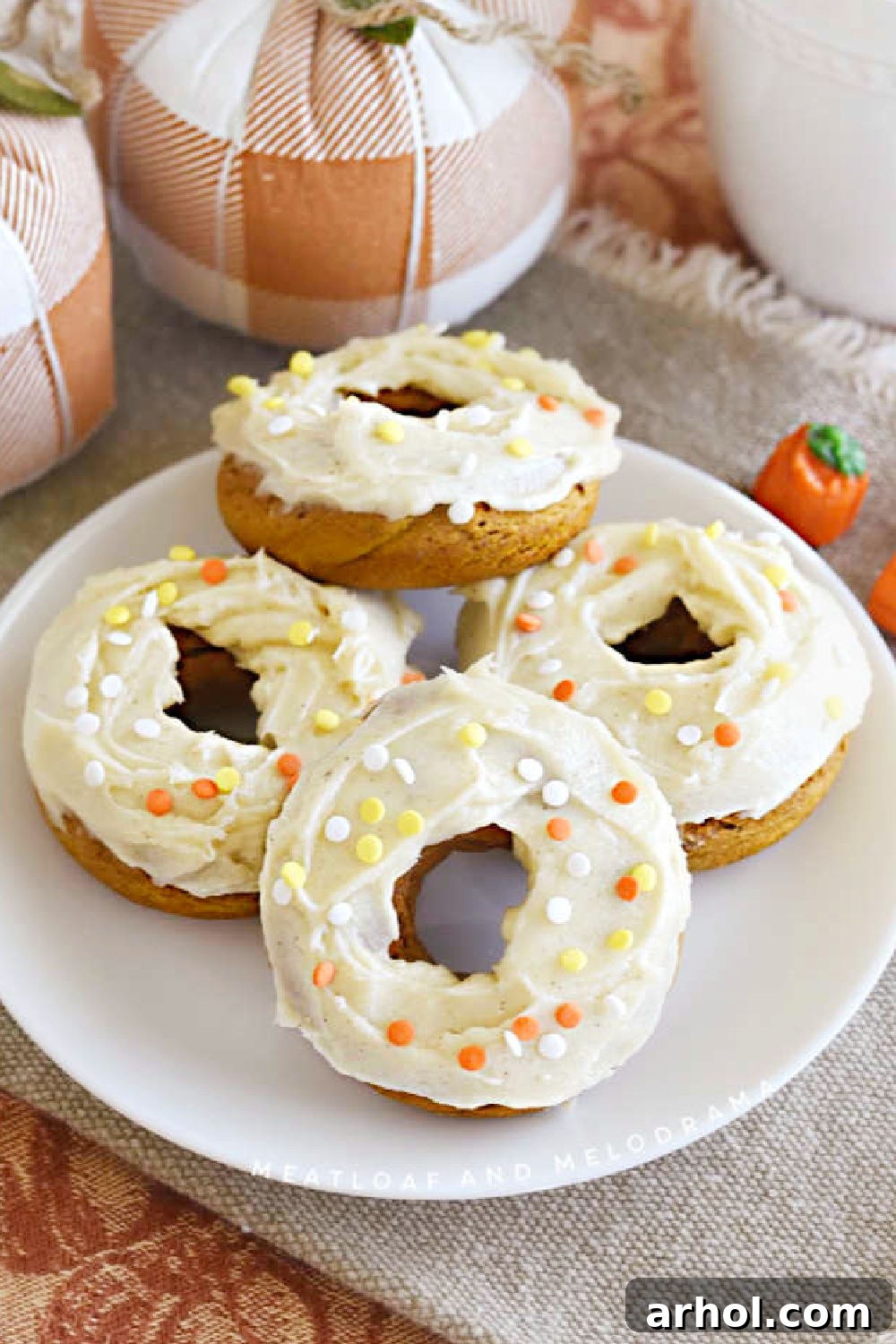 Baked pumpkin cake mix donuts with cream cheese frosting and sprinkles on platter, ready for serving