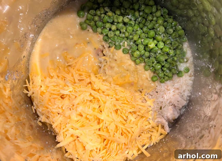 Dreamy Instant Pot Cheesy Chicken and Rice 5 Melted shredded cheddar cheese and vibrant green peas stirred into the creamy chicken and rice mixture in the Instant Pot.