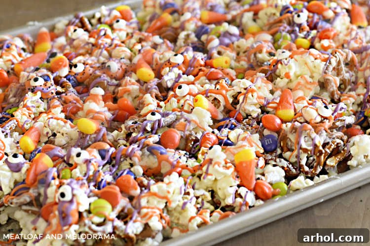 Monster Munch Halloween popcorn spread on a baking sheet with colorful drizzles and candy